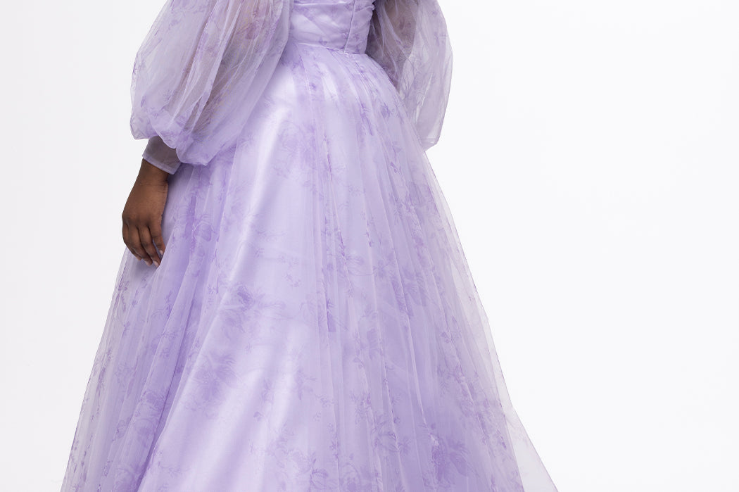 Sydney's Closet style SC7445 in lilac purple floral. 

Plus size A-line strapless formal dress in tulle.  Strapless, pleated, sweetheartneckline, natural waistline, A-line skirt with slit and pockets with detachable puff sleeves.