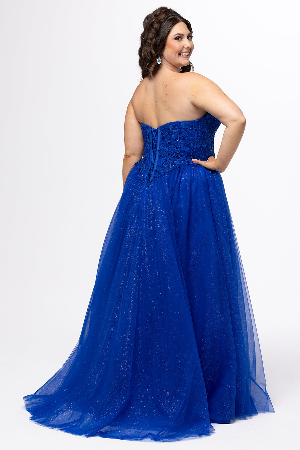 Sydney's Closet style SC7450 in royal blue.

Ball gown silhouette, strapless bodice with deep V-mesh insert covered in lace appliques and exposed corset boning. Basque waistline and full sparkle tulle a-line skirt. Lace up back with modesty panel. 