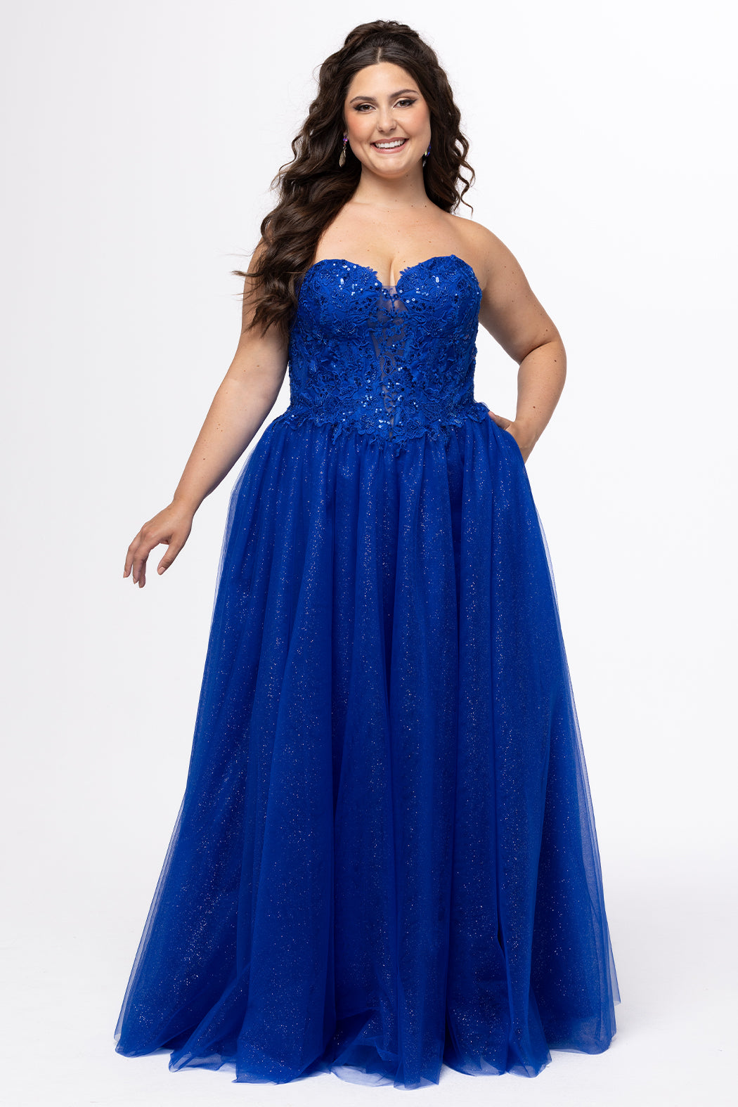 Sydney's Closet style SC7450 in royal blue.

Ball gown silhouette, strapless bodice with deep V-mesh insert covered in lace appliques and exposed corset boning. Basque waistline and full sparkle tulle a-line skirt. Lace up back with modesty panel. 