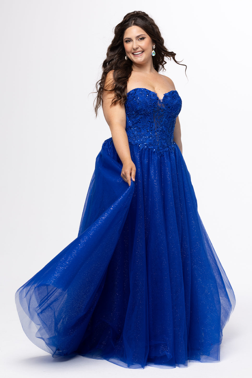 Sydney's Closet style SC7450 in royal blue.

Ball gown silhouette, strapless bodice with deep V-mesh insert covered in lace appliques and exposed corset boning. Basque waistline and full sparkle tulle a-line skirt. Lace up back with modesty panel. 
