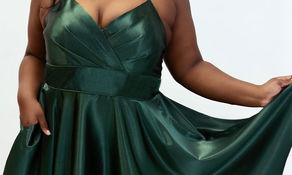 This is SC8124 in our Sydney's Closet Homecoming collection. This plus size party dress comes in black, red, green, and blue! This dress has spaghetti straps, a v neckline, and a beautiful rouched bodice! This a-line satin gown flows beautifully with your dance moves! With the length hitting right at your knees, and pockets, it is the perfect dress for this homecoming season!