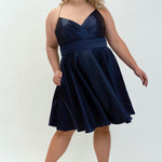 This is SC8124 in our Sydney's Closet Homecoming collection. This plus size party dress comes in black, red, green, and blue! This dress has spaghetti straps, a v neckline, and a beautiful rouched bodice! This a-line satin gown flows beautifully with your dance moves! With the length hitting right at your knees, and pockets, it is the perfect dress for this homecoming season!