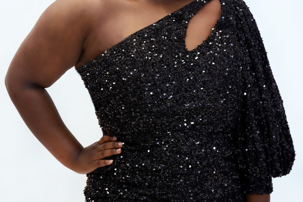 This is SC8133 in our Sydney's Closet Homecoming collection. This plus size party dress comes in black, blue, purple, and red! This dress has a one shoulder long sleeve pouf sleeve, a cutout bodice, and a natural waistline. This fitted all over sequin dress has the spotlight as the most perfect dress for this homecoming season!