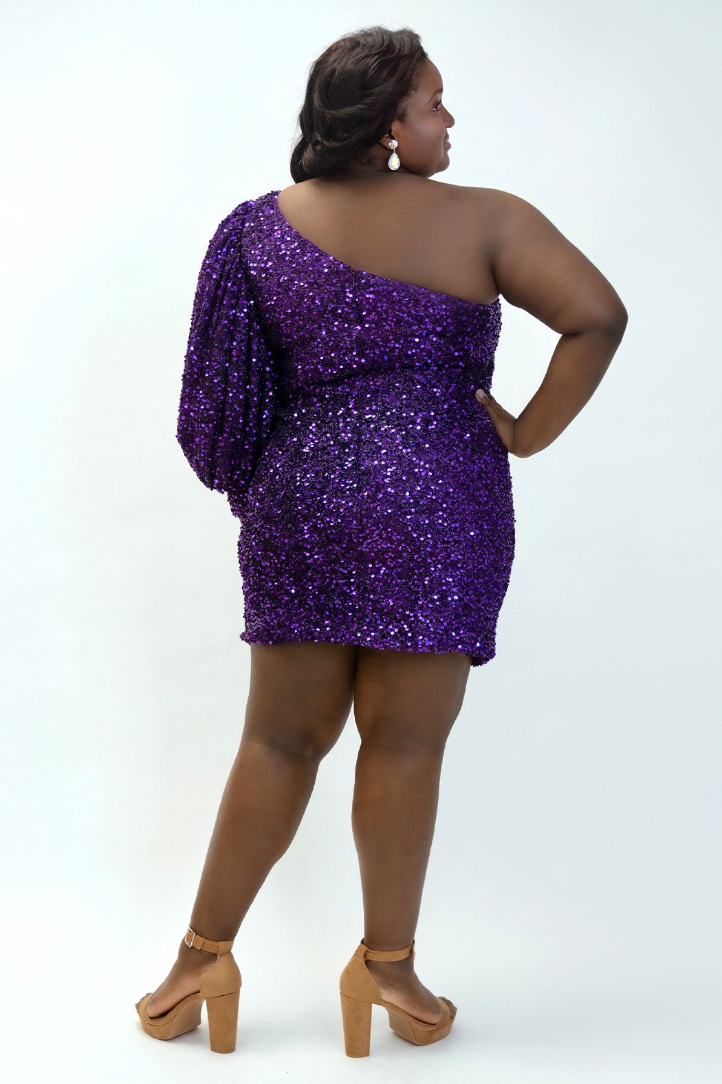 This is SC8133 in our Sydney's Closet Homecoming collection. This plus size party dress comes in black, blue, purple, and red! This dress has a one shoulder long sleeve pouf sleeve, a cutout bodice, and a natural waistline. This fitted all over sequin dress has the spotlight as the most perfect dress for this homecoming season!