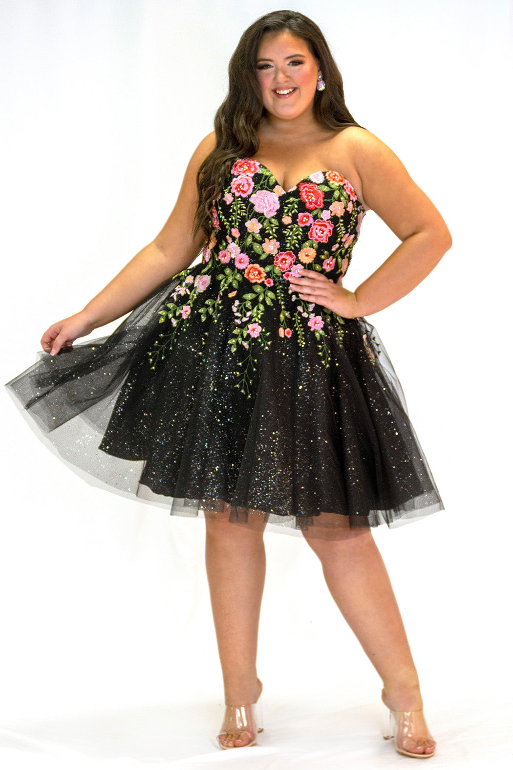 SC8137 Front view. Black sparkle tulle short a-line party dress with pink floral embroidered roses. Strapless sweetheart neckline, long invisible center back zipper.  Available only in black floral. Curvy sizes 10-32. Model in picture is 5 foot 9 inches and a size 16.