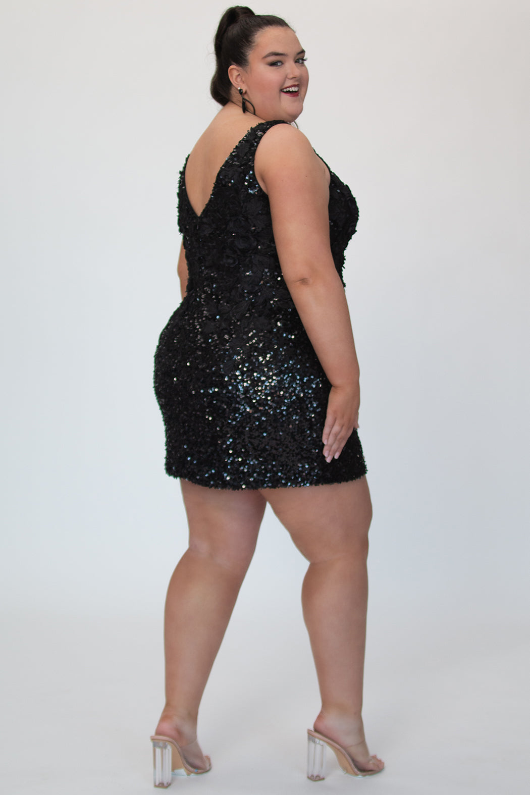 Short fitted Onyx black party dress SC8145 by Sydney's Closet. Back view.  Fully sequined short gown, with 3D floral embellishments on bodice. Thick bra-friendly straps, deep v-neckline. Long invisible center back zipper. Availability in lilac purple, onyx black and ruby red . Model in picture is 5'9. 