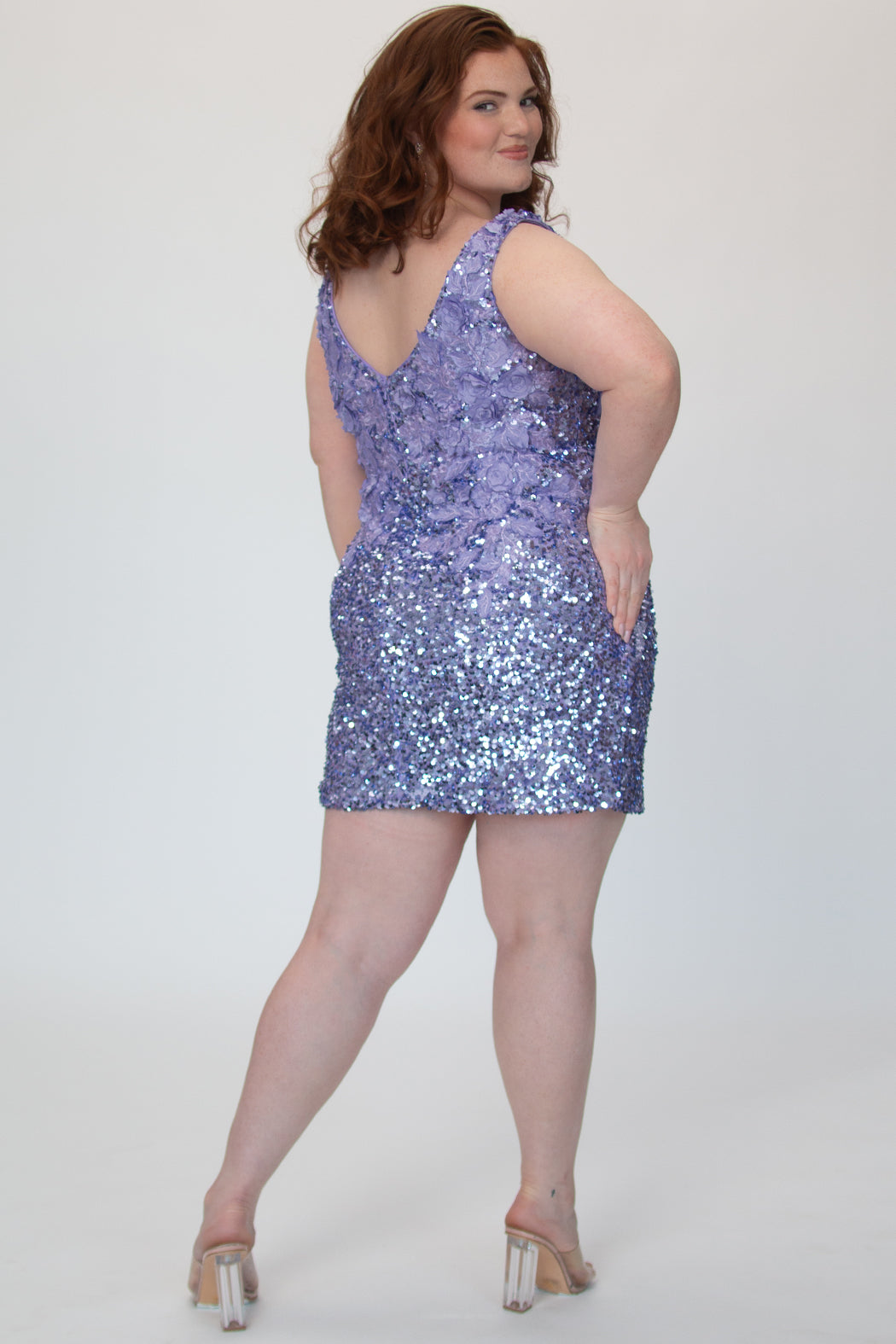 Short fitted lilac purple party dress SC8145 by Sydney's Closet. Back view.  Fully sequined short gown, with 3D floral embellishments on bodice. Thick bra-friendly straps, deep v-neckline. Long invisible center back zipper. Availability in lilac purple, onyx black and ruby red . Model in picture is 5'9. 