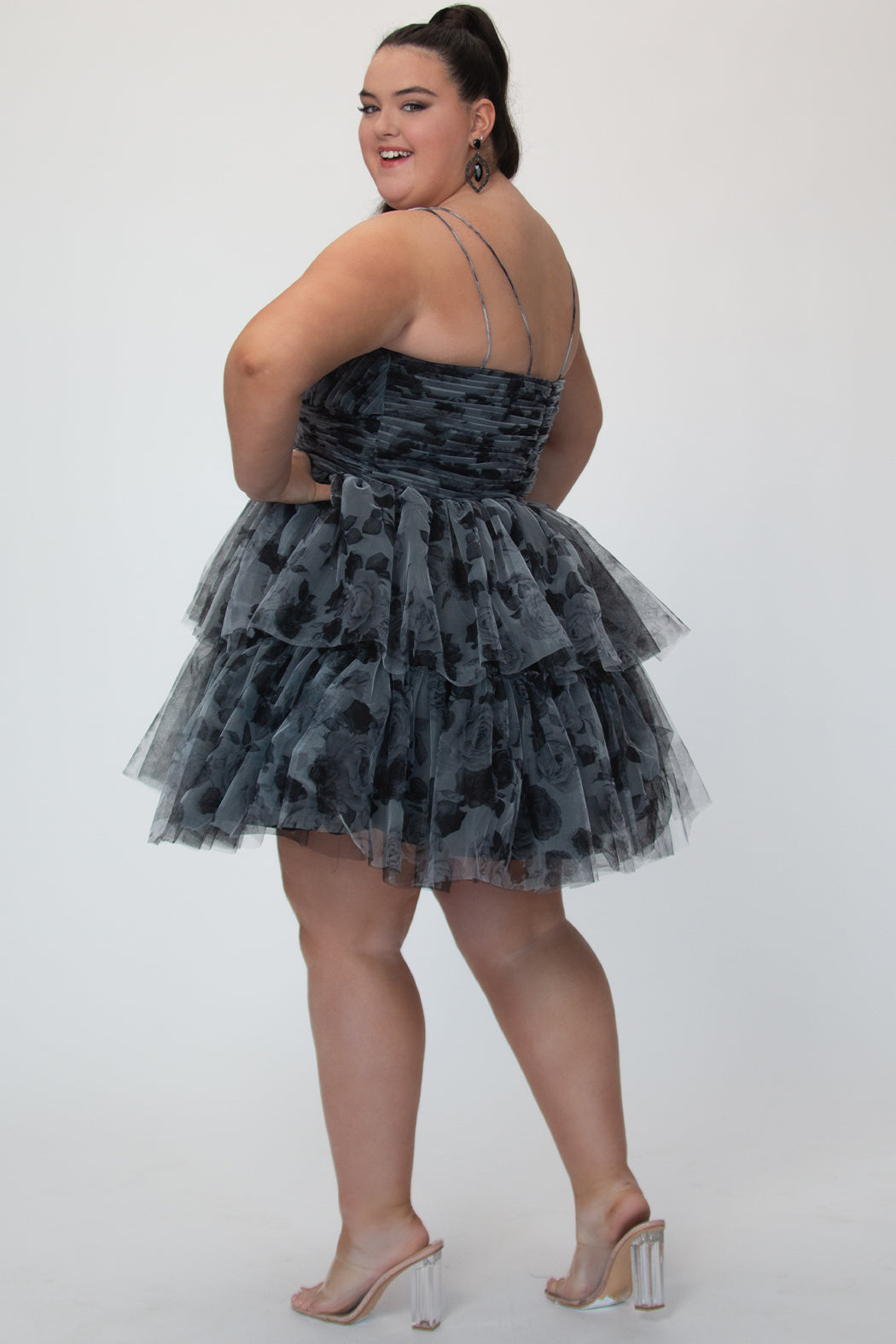 Tiered floral short party dress, SC8151 by Sydney's Closet. Back view.  In the color Black/floral. Floral tulle fabric with a satin lining. Fully pleated bodice, sweetheart neckline, double spaghetti straps and a two-tiered skirt. Long invisible center back zipper. Available in blue/floral and black/floral sizes 14-32. 
Model is 5'9.  