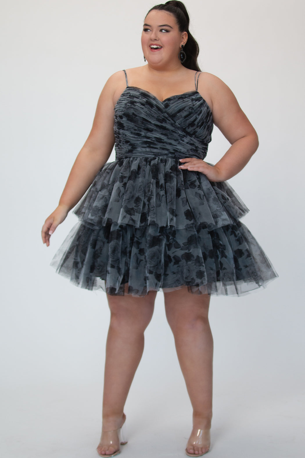 Tiered floral short party dress, SC8151 by Sydney's Closet. Front view. In the color Black/floral. Floral tulle fabric with a satin lining. Fully pleated bodice, sweetheart neckline, double spaghetti straps and a two-tiered skirt. Long invisible center back zipper. Available in blue/floral and black/floral sizes 14-32. 
Model is 5'9. 