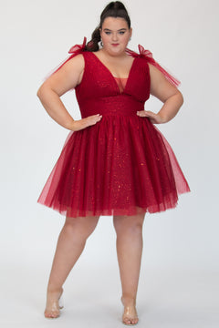 Short A-line plus size flowy party dress SC8153 by Sydney's Closet in the color Firecracker red. Front view. Layers of dense sparkle tulle and a satin lining. V-neckline with thick bra-friendly straps and detachable bows at the top of the shoulder. Pleated bodice and 3 inch pleated waistband. Pockets and long invisible center back zipper. Available in Shamrock green, Admiral blue and firecracker red, sizes 14-32.
Model is 5'9. 