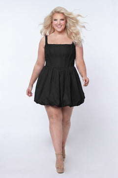 Plus-size model wearing a black sleeveless taffeta mini dress with a square neckline, structured corset-inspired bodice with exposed boning, and voluminous bubble hem skirt. She is styled with long flowing blonde hair, drop earrings, and nude platform ankle-strap heels, walking toward the camera against a light gray studio background. Front view.

Sydney's Closet SC8166 in black