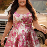 Plus-size model wearing a sleeveless a-line mini dress with a scoop neckline and metallic floral brocade pattern in shades of pink, fuchsia, and champagne. She is styled with a pink glitter cowboy hat, long flowing dark brown hair, dangling earrings, and nude ankle-strap heels. The model walks through a rustic autumn setting with pumpkins, hay bales, and a vintage tan truck in the background.

Sydney's Closet SC8169 in pink floral
