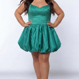 Plus-size model wearing a emerald green sleeveless mini dress with a V-neckline, rhinestone & pearl embellished fitted bodice, and a voluminous bubble hem skirt. She is styled with long wavy brown hair, dangling crystal earrings, and nude platform ankle-strap heels, posing against a light gray studio background while her hands are on her hips.

Sydney's Closet SC8171 in green