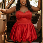 Plus-size model wearing a red spaghetti-strap mini dress with a sweetheart neckline, fitted rhinestone-embellished bodice, and voluminous bubble hem skirt. She is styled with a white cowboy hat, long wavy black hair, and dangling earrings, posing in the open doorway of a vintage tan truck. The outdoor setting features warm natural light and a rustic country-inspired aesthetic.

Sydney's Closet SC8171 in red