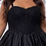 Plus-size model wearing a black sleeveless mini dress with a structured corset-style bodice and sweetheart neckline. The dress features lace detailing on the bodice and a voluminous satin bubble hem skirt. She is styled with long wavy dark brown hair, dangling earrings, and clear open-toe heels, posing against a light gray studio background while holding the sides of the skirt. Detail view. 

Sydney's Closet SC8173