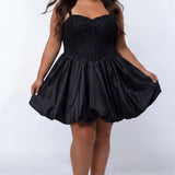 Plus-size model wearing a black sleeveless mini dress with a structured corset-style bodice and sweetheart neckline. The dress features lace detailing on the bodice and a voluminous satin bubble hem skirt. She is styled with long wavy dark brown hair, dangling earrings, and clear open-toe heels, posing against a light gray studio background while holding the sides of the skirt. Front view. 

Sydney's Closet SC8173