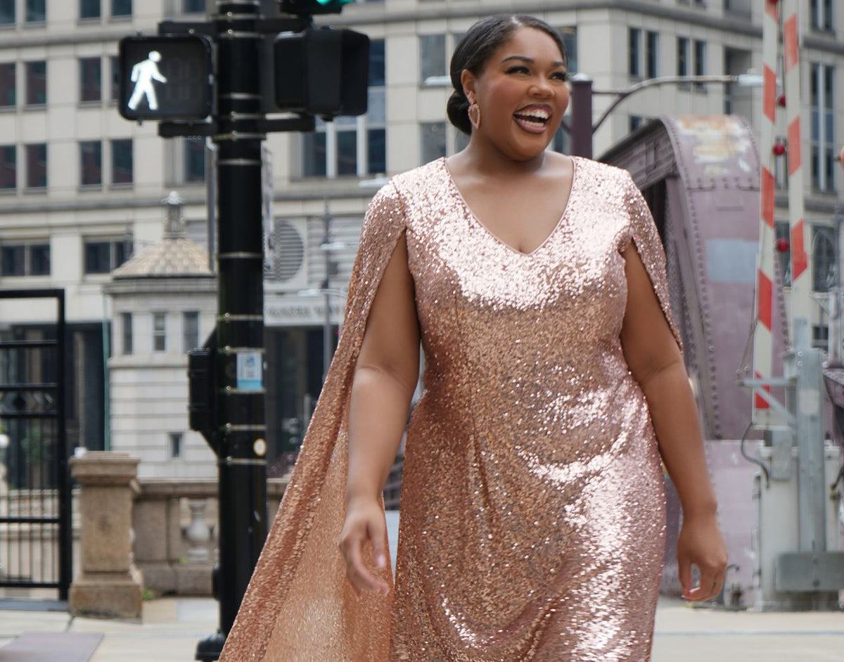 Woman in a sequin rose gold dress walking on a city street.