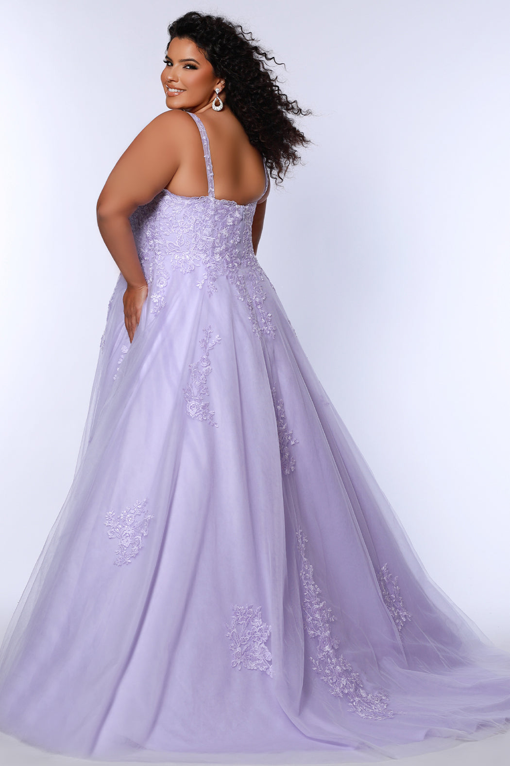 Plus size lace and tulle ball gown by Tease Prom.  Style TE2526 available in lilac purple or sage green.  Deep v-neckline with nude mesh insert. Wide straps and bodice fully covered with appliques.  Bodice is unlined but ships with optional lining panel.  Full A-line skirt with scattered lace appliques, pockets and chapel train. 