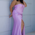 Sexy fitted pastel plus size prom dress by Tease Prom. Style TE2528. Strapless  bodice with assymetrical basque waistline. Exposed corset boning and bustier bodice is fully lined.  Ruchsing and knot detail at the waistline and high slit with sweep train on a fitted skirt.  Tease Prom style TE2528 is available in lavender purple or sky blue in plus sizes 14-24. 