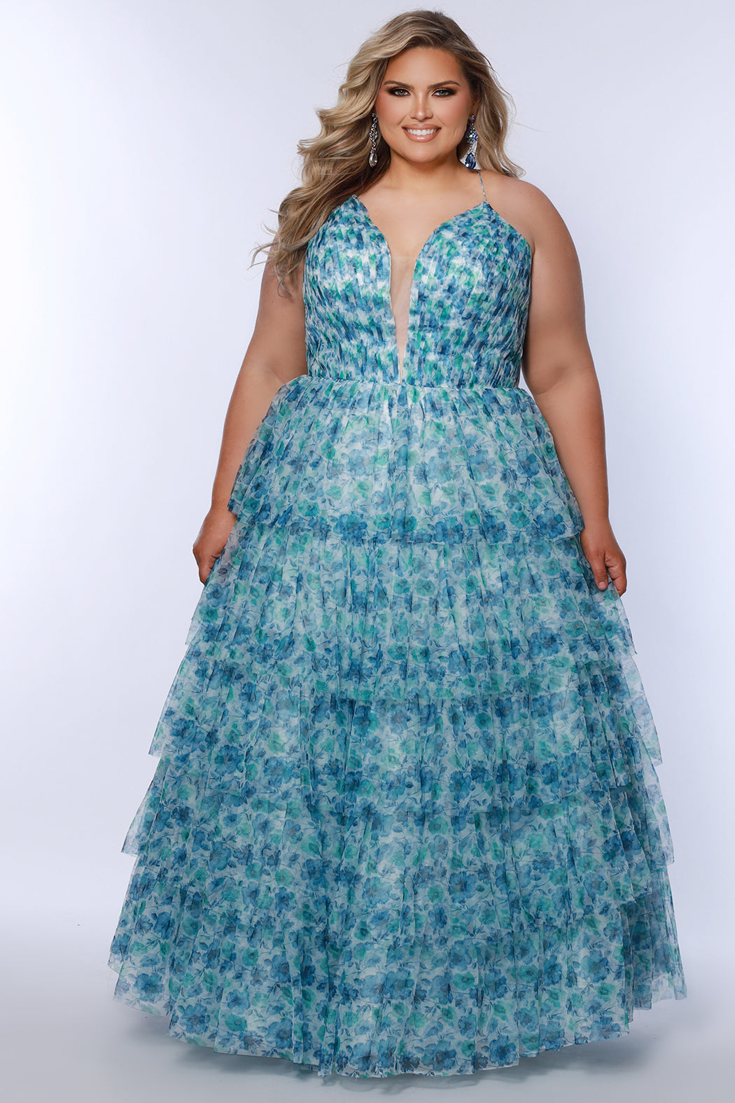 Plus size floral tiered ball gown for Prom. Tease Prom style TE2530 available in blue floral and pink floral in sizes 14-32.  Pleated deep V bodice with nude illusion mesh, natural waistline and tiered full ball gown skirt.  Spaghetti straps go into a lace up back with a modesty panel. 