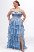 A teen modeling a strapless formal dress with a beaded sweetheart neckline, exposed corset boning, basque waistline and a full tiered chiffon ruffle skirt, photographed against a light gray studio background.

TE2611 in bluejay light blue by Tease Prom, exclusively plus size prom dresses designed by Sydney's Closet.