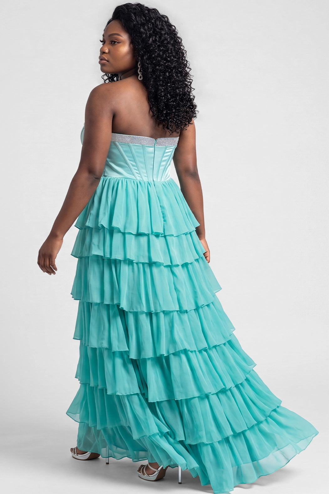 A teen modeling a strapless formal dress with a beaded sweetheart neckline, exposed corset boning, basque waistline and a full tiered chiffon ruffle skirt, photographed against a light gray studio background.

TE2611 in seafoam green by Tease Prom, exclusively plus size prom dresses designed by Sydney's Closet.