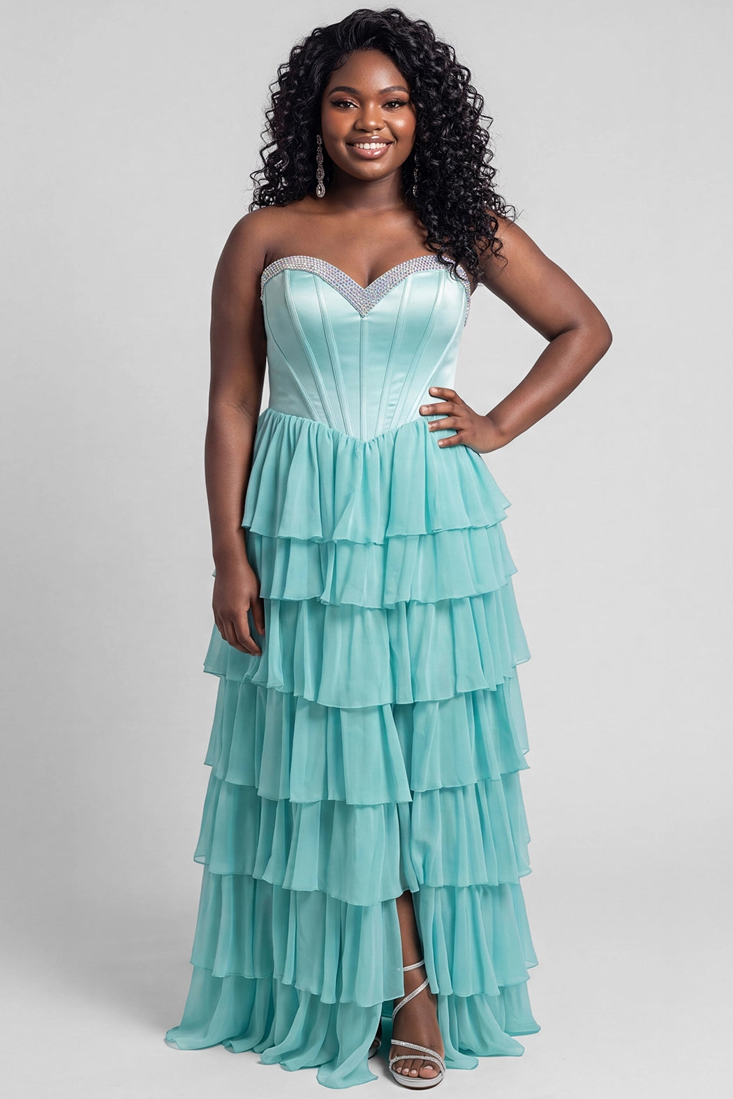 A teen modeling a strapless formal dress with a beaded sweetheart neckline, exposed corset boning, basque waistline and a full tiered chiffon ruffle skirt, photographed against a light gray studio background.

TE2611 in seafoam green by Tease Prom, exclusively plus size prom dresses designed by Sydney's Closet.