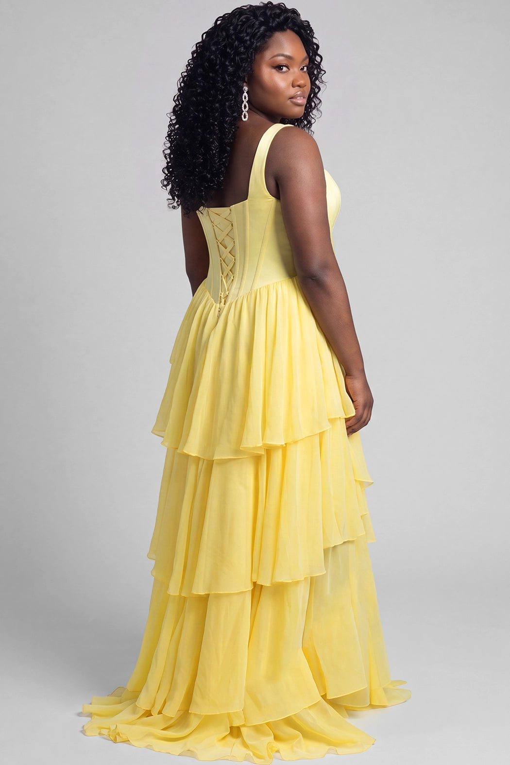 A teen modeling a bright yellow sleeveless formal prom dress with scoop neckline, a structured bodice, layered ruffle skirt, and high slit, photographed against a solid light gray studio background.

TE2704 in yellow by Tease Prom, exclusively plus size prom dresses designed by Sydney's Closet.