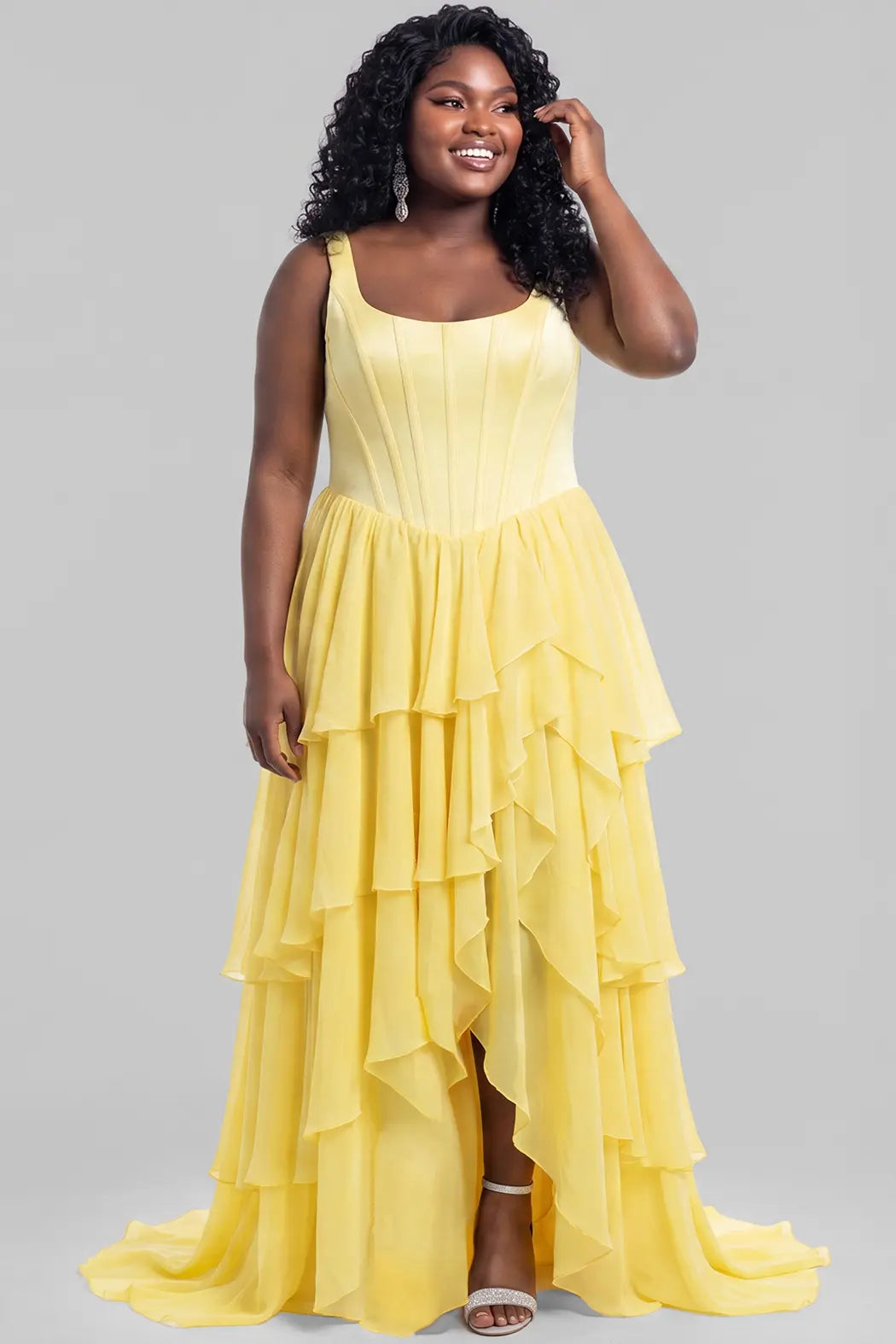 A teen modeling a bright yellow sleeveless formal prom dress with scoop neckline, a structured bodice, layered ruffle skirt, and high slit, photographed against a solid light gray studio background.

TE2704 in yellow by Tease Prom, exclusively plus size prom dresses designed by Sydney's Closet.