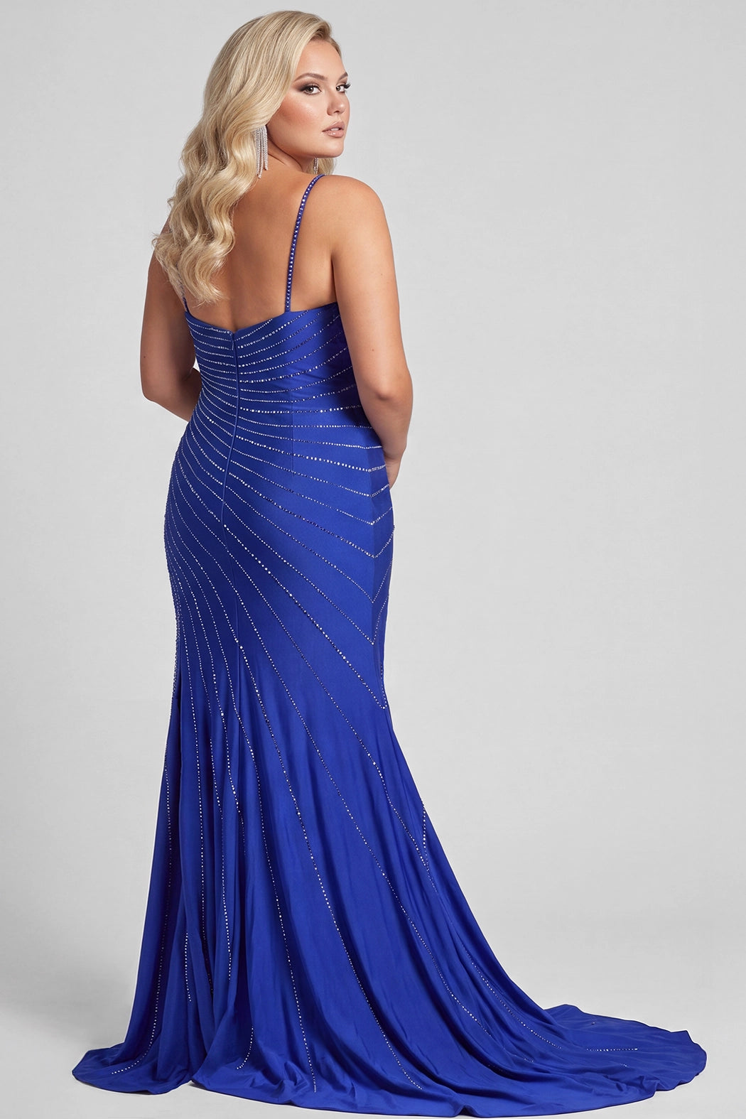 A blonde teen modeling a royal blue floor-length formal gown with thin straps, a sweetheart neckline, diagonal silver hot fix stone embellishments, and a high front slit, photographed against a light gray studio background.

TE2705 in royal by Tease Prom, exclusively plus size prom dresses designed by Sydney's.