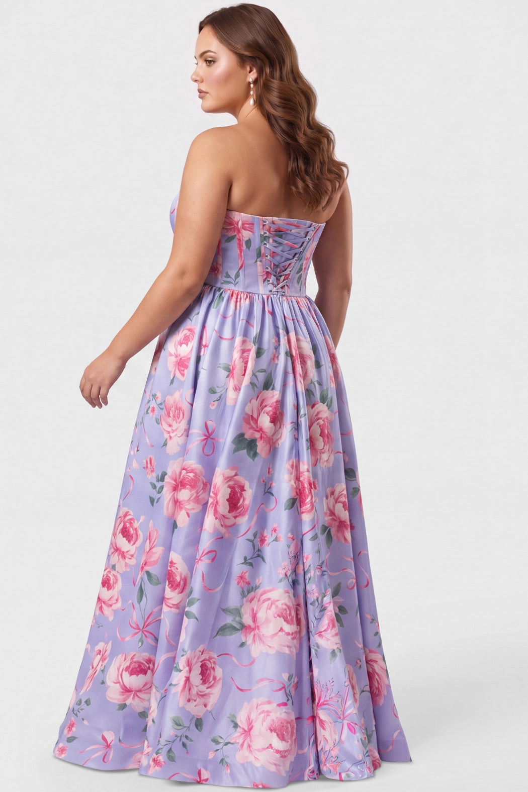 A brunette teen modeling a strapless blue floral prom dress with a pink and green floral print, featuring a sweetheart neckline, fitted bodice with exposed corset boning, basque waisltine, and a high thigh slit, set against a plain light gray studio background.

TE2707 in blue floral by Tease Prom, exclusively plus size prom dresses designed by Sydney's Closet.