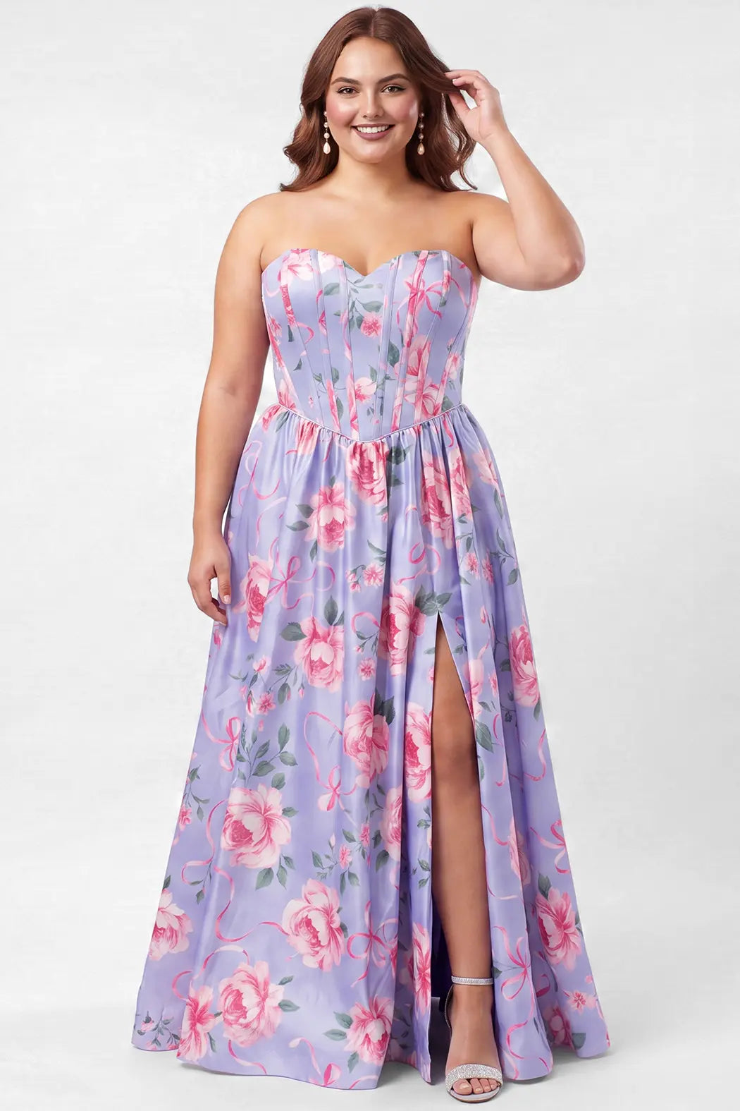 A brunette teen modeling a strapless blue floral prom dress with a pink and green floral print, featuring a sweetheart neckline, fitted bodice with exposed corset boning, basque waisltine, and a high thigh slit, set against a plain light gray studio background.

TE2707 in blue floral by Tease Prom, exclusively plus size prom dresses designed by Sydney's Closet.