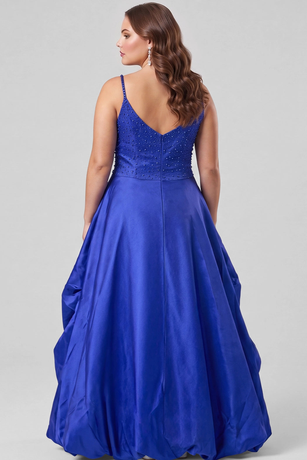 A teenager modeling a royal blue ball gown with a pearl and beaded sweetheart bodice, spaghetti straps, drop waistline and a high-low ruffled hemline, photographed against a light gray studio background.

TE2713 in cobalt blue by Tease Prom, exclusively plus size prom dresses designed by Sydney's Closet.