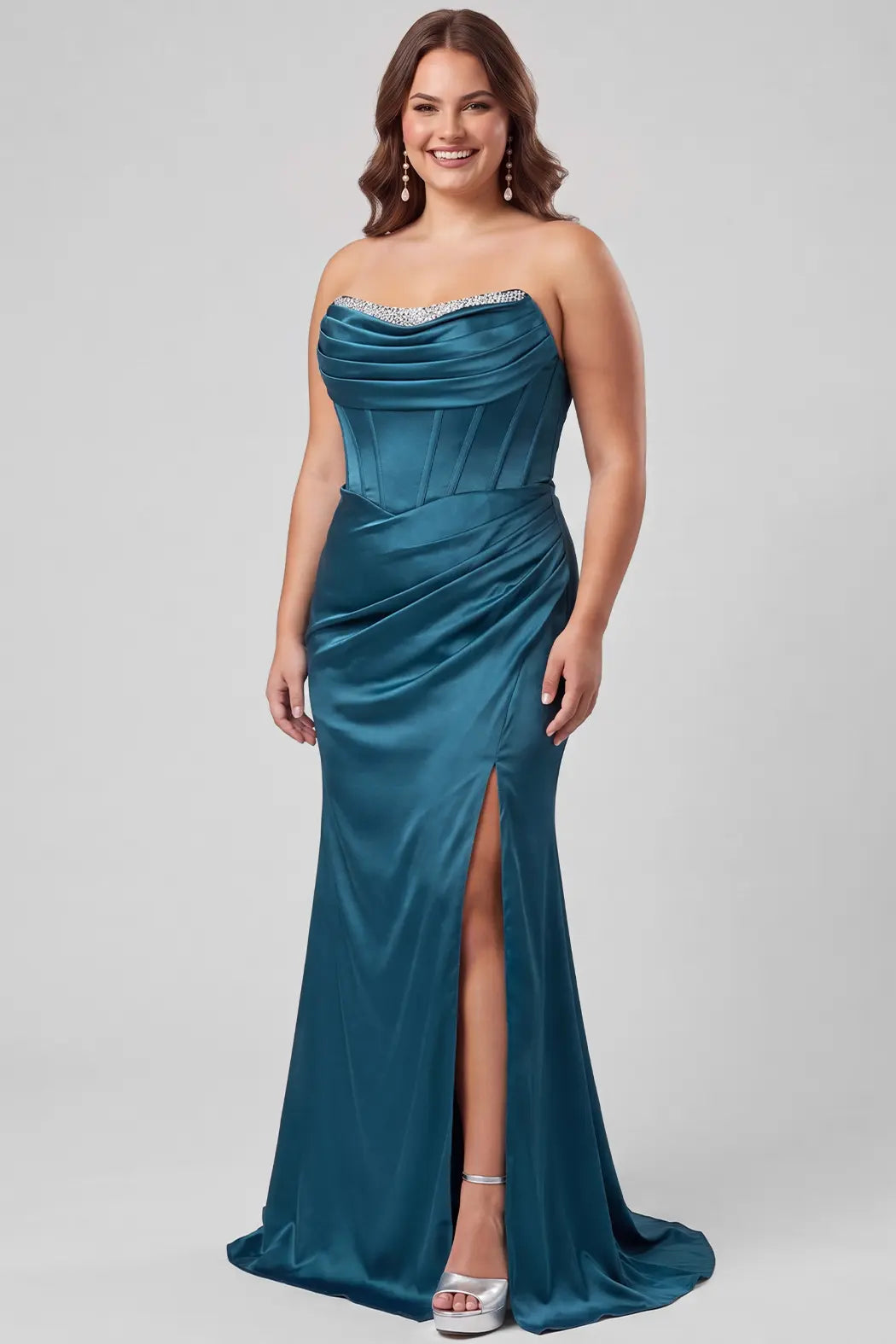 A teen models a floor-length teal satin gown with a sweetheart neckline, embellished bodice, draped skirt, and high front slit against a light gray studio background.

TE2716 in teal by Tease Prom, exclusively plus size prom dresses designed by Sydney's Closet.