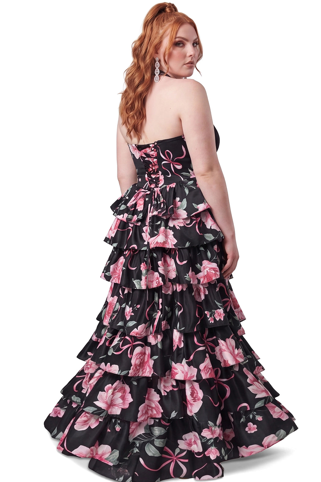A teen modeling a sleeveless black halter gown with a tiered ruffle skirt, featuring a pink and green floral print on black satin, against a plain white background.

TE2720 in black floral by Tease Prom, exclusively plus size prom dresses designed by Sydney's Closet.