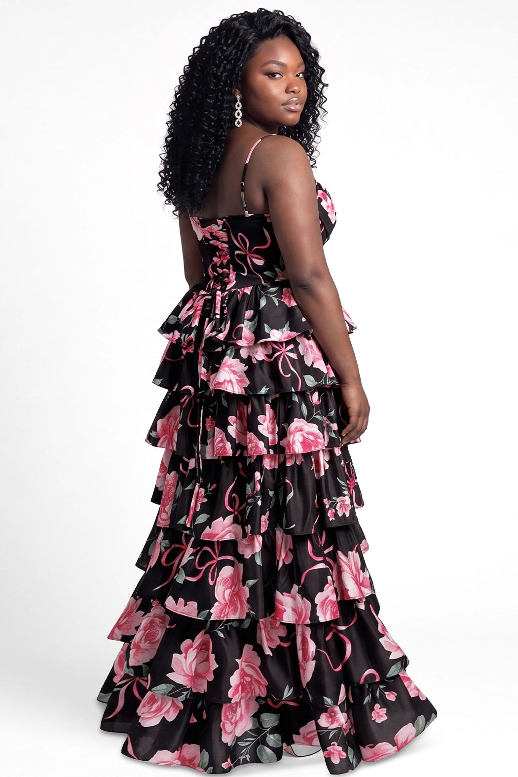 A teen  modeling a long black chiffon tiered gown with a pink and green floral print on black background, photographed against a plain light gray studio background.

TE2721 in black floral by Tease Prom, exclusively plus size prom dresses designed by Sydney's Closet.