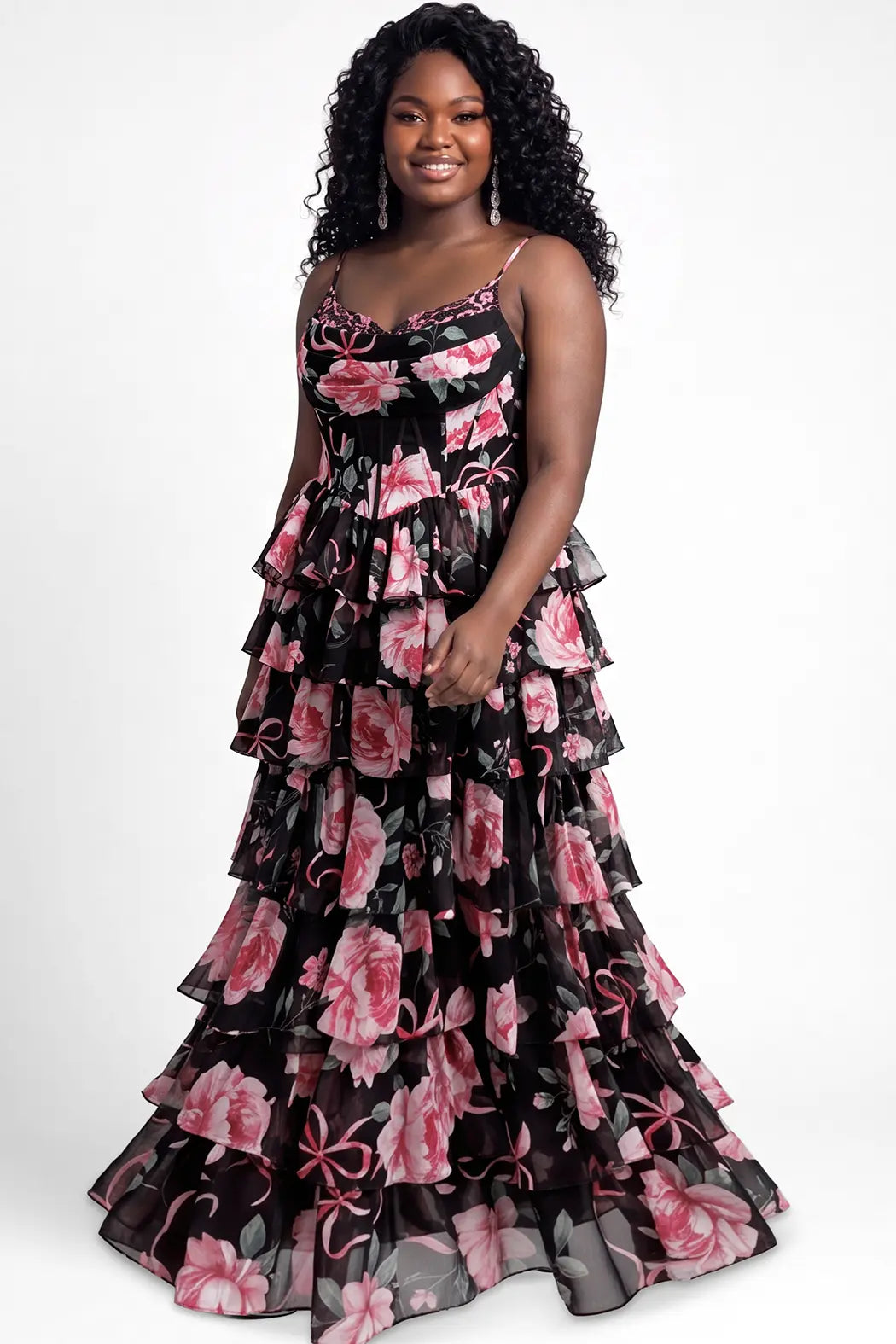A teen  modeling a long black chiffon tiered gown with a pink and green floral print on black background, photographed against a plain light gray studio background.

TE2721 in black floral by Tease Prom, exclusively plus size prom dresses designed by Sydney's Closet.
