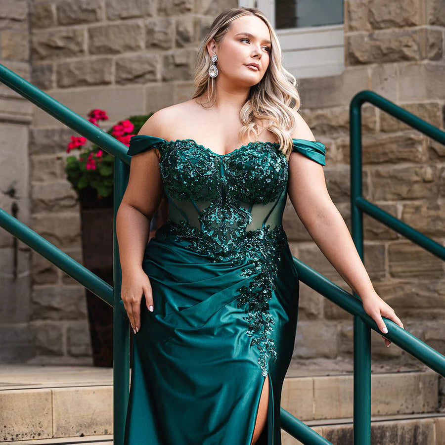 Sydney's Closet UK Capsule collection UK2616 emerald green plus size prom dress

Woman in a teal evening gown standing on steps with a stone wall and green railing in the background.