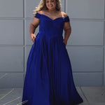 Long formal satin ballgown style SC7400 by Sydney's Closet. Available in sizes 14-32 in colors cobalt blue, onyx black and ruby red.  Pleated bodice with exposed boning, detachable pleated drape sleeves, basque waist and pockets.  
