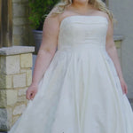 Video montage of a bride modeling a strapless A-line wedding gown with a subtle floral print, shown outdoors from multiple angles and distances. The text “Avia” and the “Sydney's Closet” logo appear at the bottom.