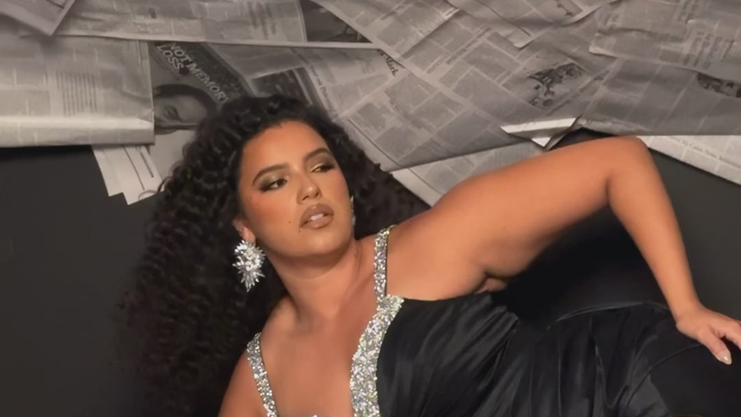 Plus Size satin fitted pleated formal dress with silver beaded straps and V-neckline detail. Pleated bodice, ruching on fitted skirt with slit. Attached overskirt included. Avialablie in fire red, magenta pink, onyx black, and sky blue in plus sizes 14-28. Style TE2513 by Tease Prom. 