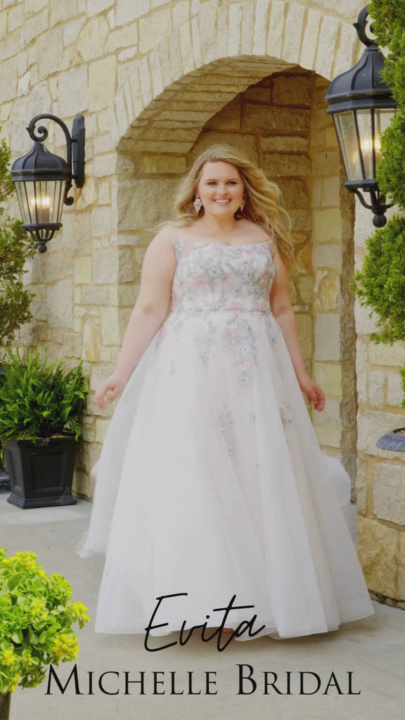 Plus-size bride wearing the Michelle Bridal MB2614 Evita wedding gown with pastel blue and pink embroidered lace appliqués on the bodice, a strapless scoop neckline, and a sparkle tulle A-line skirt.