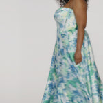 Woman models a strapless A-line gown with a teal and blue floral print, spinning to show the full skirt before walking off screen.