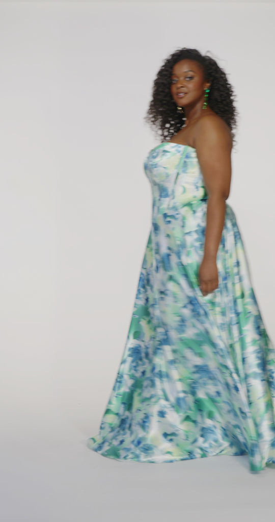 Woman models a strapless A-line gown with a teal and blue floral print, spinning to show the full skirt before walking off screen.