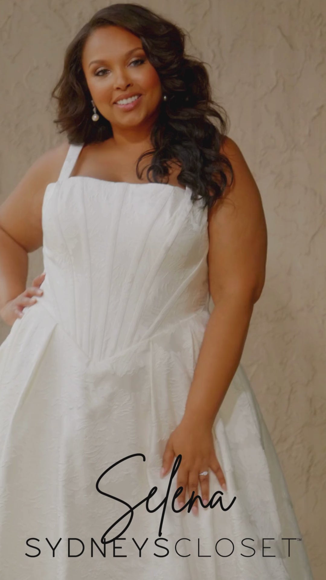 Video montage of a bride modeling an A-line wedding gown with an exposed corset bodice and a subtle floral print, shown outdoors from multiple angles and distances. The text “Selena” and the “Sydney's Closet” logo appear at the bottom.
