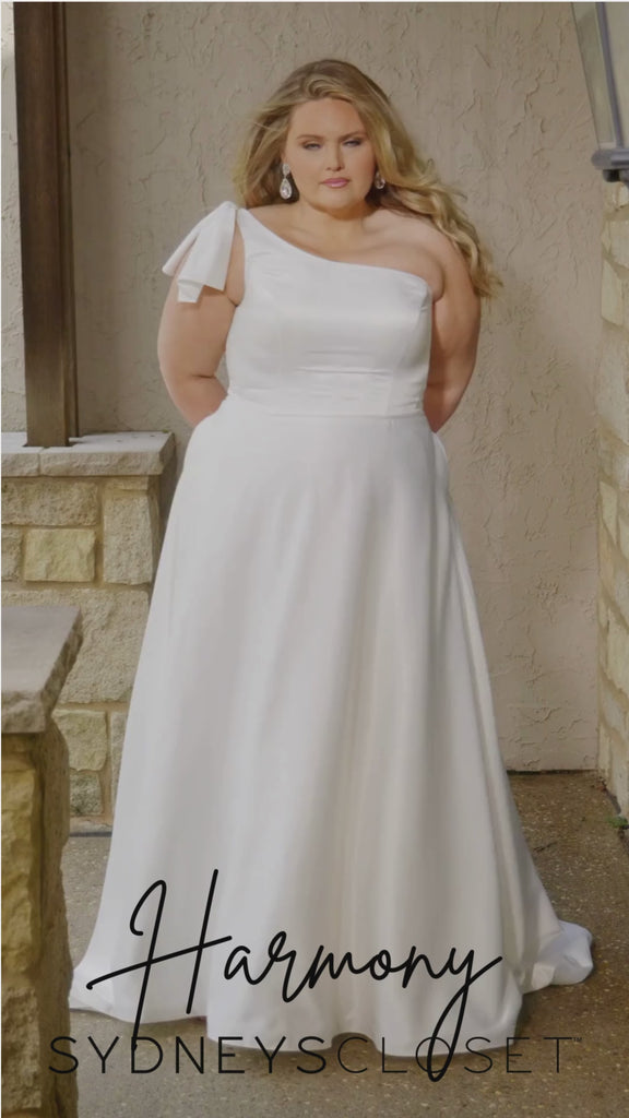 Video montage of a bride modeling a simple white one shoulder A-line wedding gown with a strap detail, shown outdoors from multiple angles and distances. The text “Harmony” and the “Sydney's Closet” logo appear at the bottom.