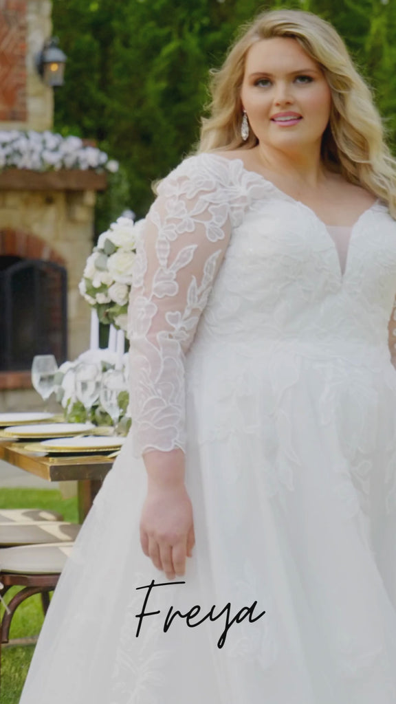 Plus-size bride modeling the MB2604 wedding gown by Michelle Bridal, featuring a structured bodice and elegant flowing silhouette designed for curvy brides.
