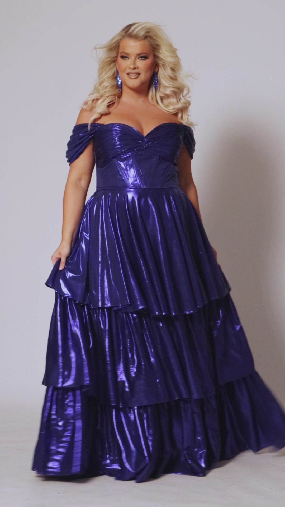 Plus size metallic tiered prom dress.  Strapless bodice with pleating and exposed boning. Detachable pleated drape sleeves. Available in fuchsia pink, indigo dark blue and onyx black. Style TE2510 by Tease Prom.