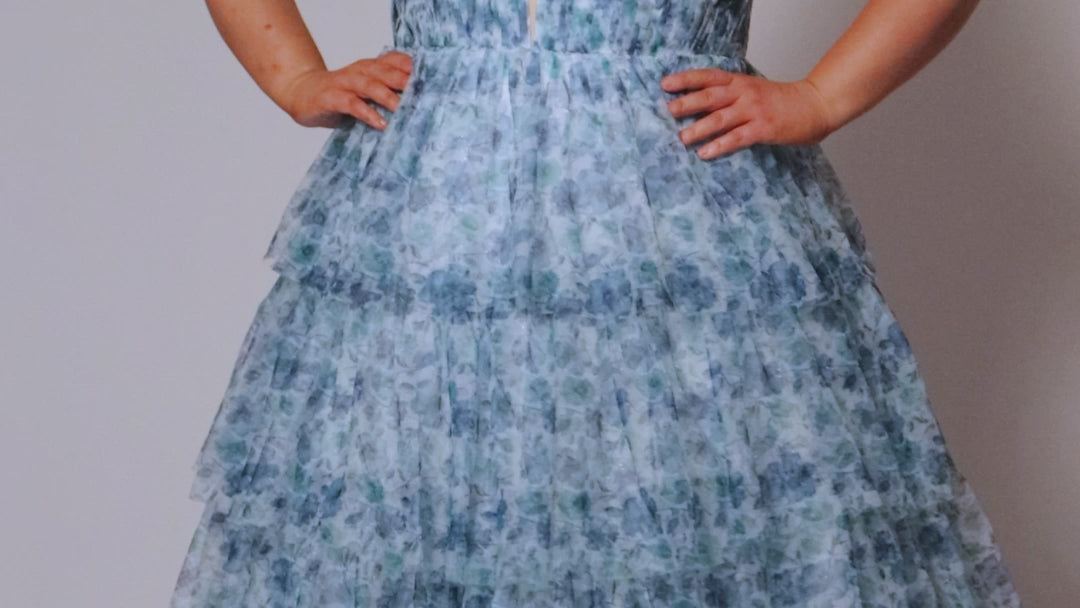 Plus size floral tiered ball gown for Prom. Tease Prom style TE2530 available in blue floral and pink floral in sizes 14-32.  Pleated deep V bodice with nude illusion mesh, natural waistline and tiered full ball gown skirt.  Spaghetti straps go into a lace up back with a modesty panel. 