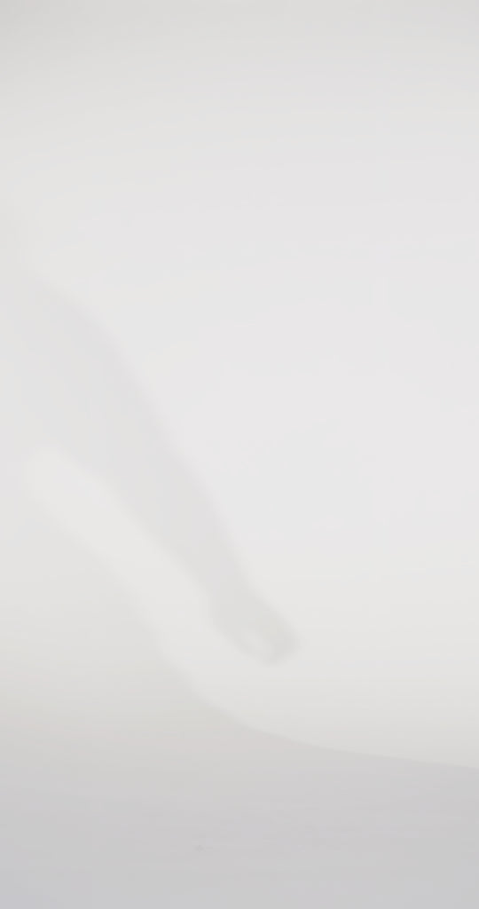 Woman models a black off-the-shoulder slim dress with a high slit, draped panel, and lace and sparkle detailing on the bodice, waving the drape panel and turning to show the lace-up back before walking off screen.